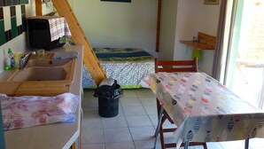 Una cucina rustica con soffitto in legno, un lavandino, un tavolo con tovaglia fantasia e una finestra vista all'esterno.