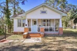 A single-story house with a front porch, a small attached garage, and a brick foundation.