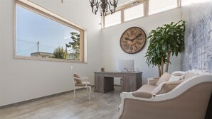 Una habitación amplia con un gran ventanal, un escritorio, una silla, un sofá y una planta en maceta.