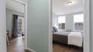 Une chambre à coucher avec un lit, une fenêtre et une porte donnant sur une autre pièce.
