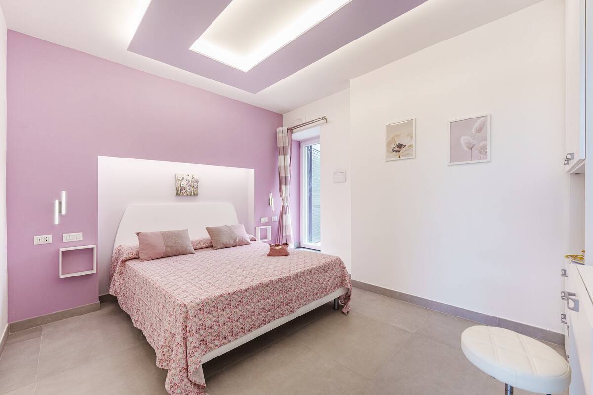 A bedroom with a bed, bedside table, and a window with curtains.