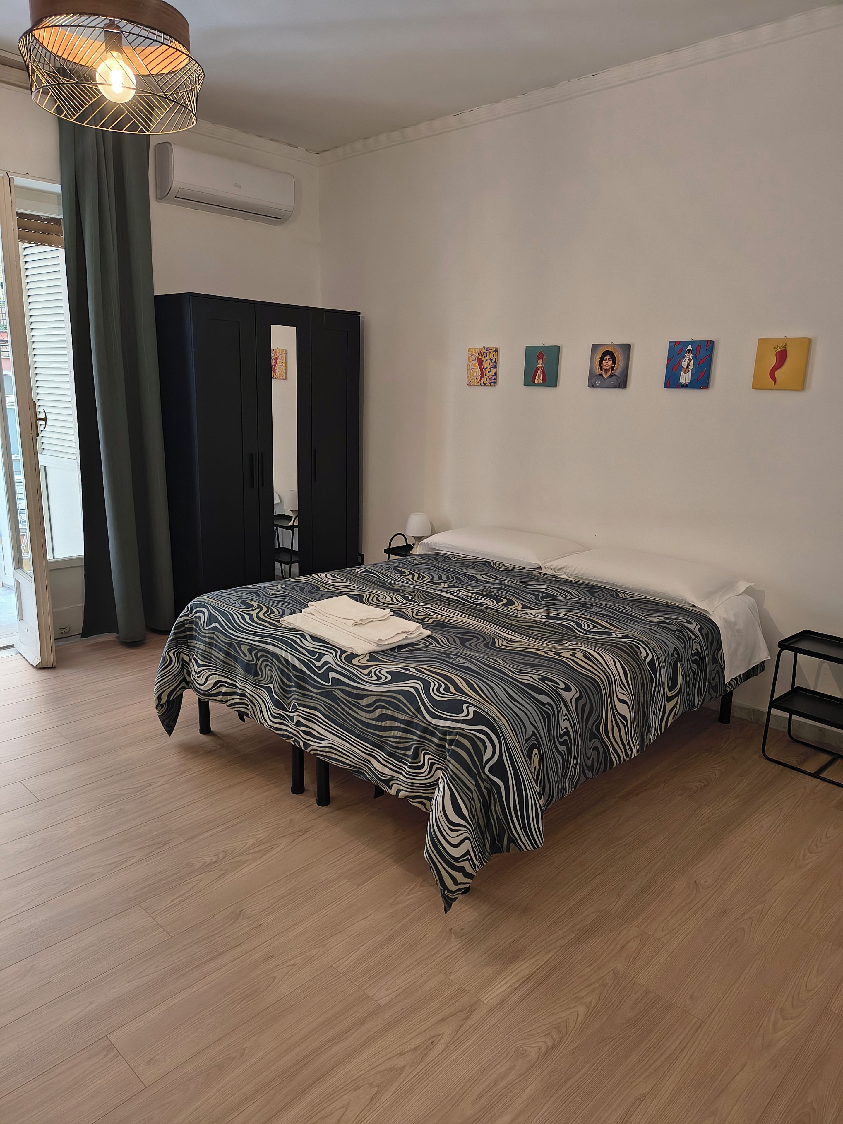 A bedroom with a bed, a wardrobe, a window with curtains, and wall art.