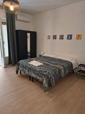 Une chambre à coucher avec un lit, une armoire, une fenêtre avec des rideaux et des œuvres d’art murales.