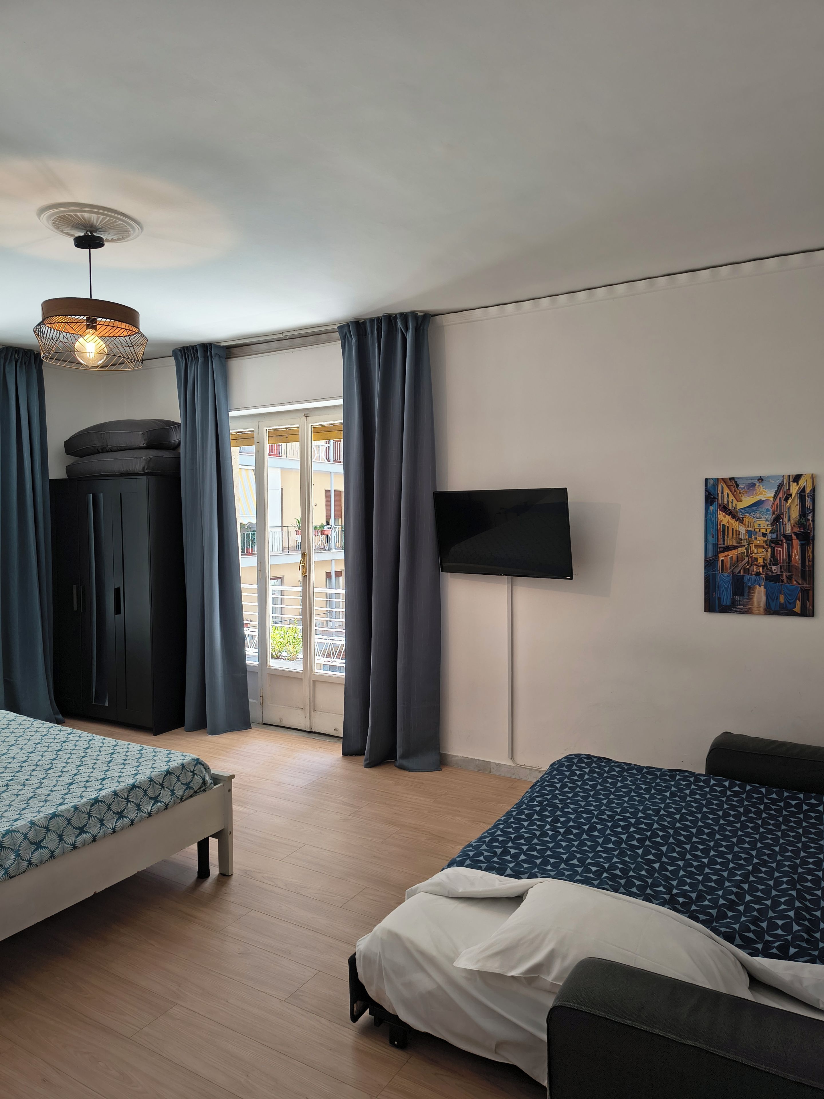 Hotellihuone, jossa on sänky, vaatekaappi, televisio ja taulu seinällä.