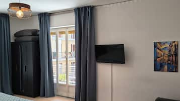 Hotellihuone, jossa on sänky, vaatekaappi, televisio ja taulu seinällä.