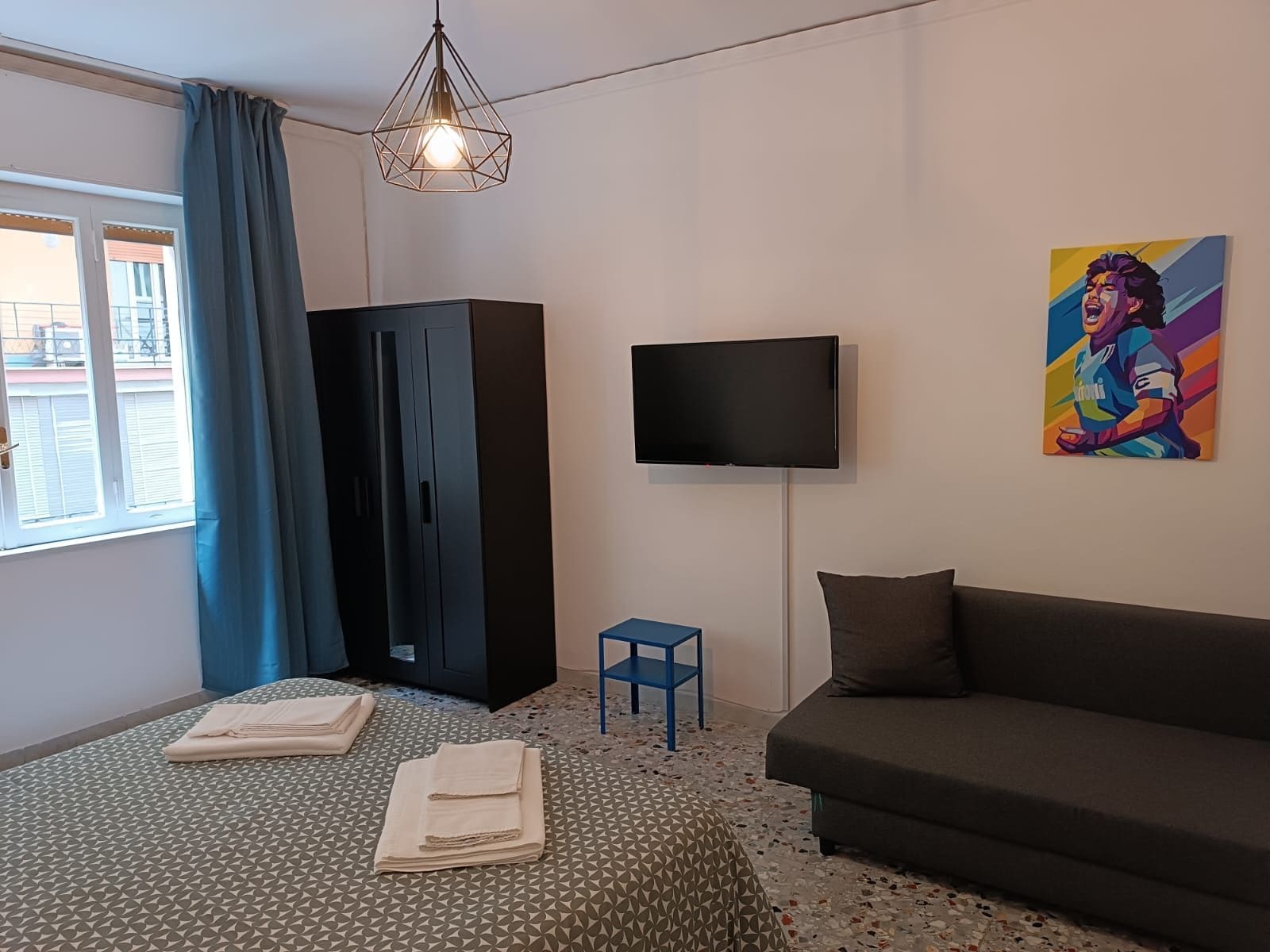 Quarto com cama, televisão, pintura e guarda-roupa.