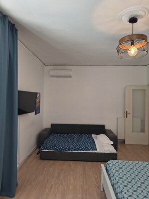 A room with a bed, a TV mounted on the wall, a ceiling light fixture, and a door. - B&B Napoli Fuorigrotta (Naples)
