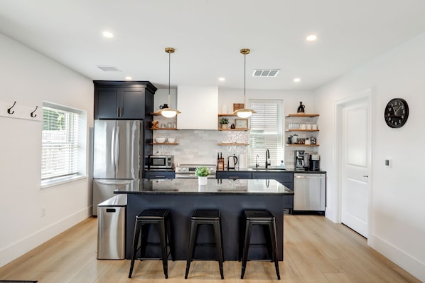 A modern kitchen with a central island, stainless steel appliances, and bar stools.