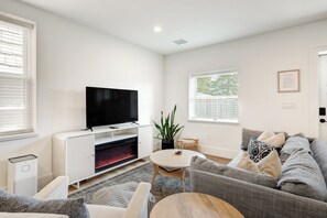 A modern living room with a flat-screen TV, a fireplace, a sofa, and a dining table. - The Loft at Legacy Manor/Minutes from Sight&Sound and Downtown Lancaster (Lancaster)