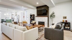 Ein modernes Wohnzimmer mit Kamin, Sofa, Couchtisch und Wand-Fernseher.