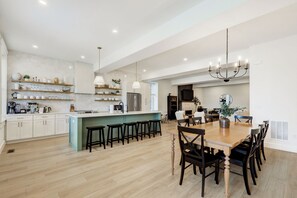 A spacious kitchen with a central island, wooden flooring, and a dining area with a large table and chairs.