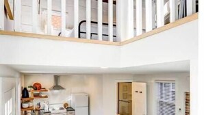 A modern apartment with a kitchen, dining area, and a living room with a sofa. - The Cottage at Legacy Manor (Lancaster)