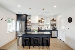 A modern kitchen with a central island, stainless steel appliances, and bar stools.