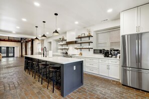 A modern kitchen with a central island, bar stools, stainless steel appliances, and a brick floor. - Legacy Manor-Sleeps 26-9 minutes to Sight&Sound,16 Minutes to Downtown Lancaster (Lancaster)