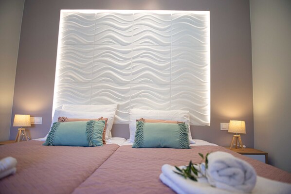 A hotel room with a large bed, two bedside tables with lamps, and a textured headboard.