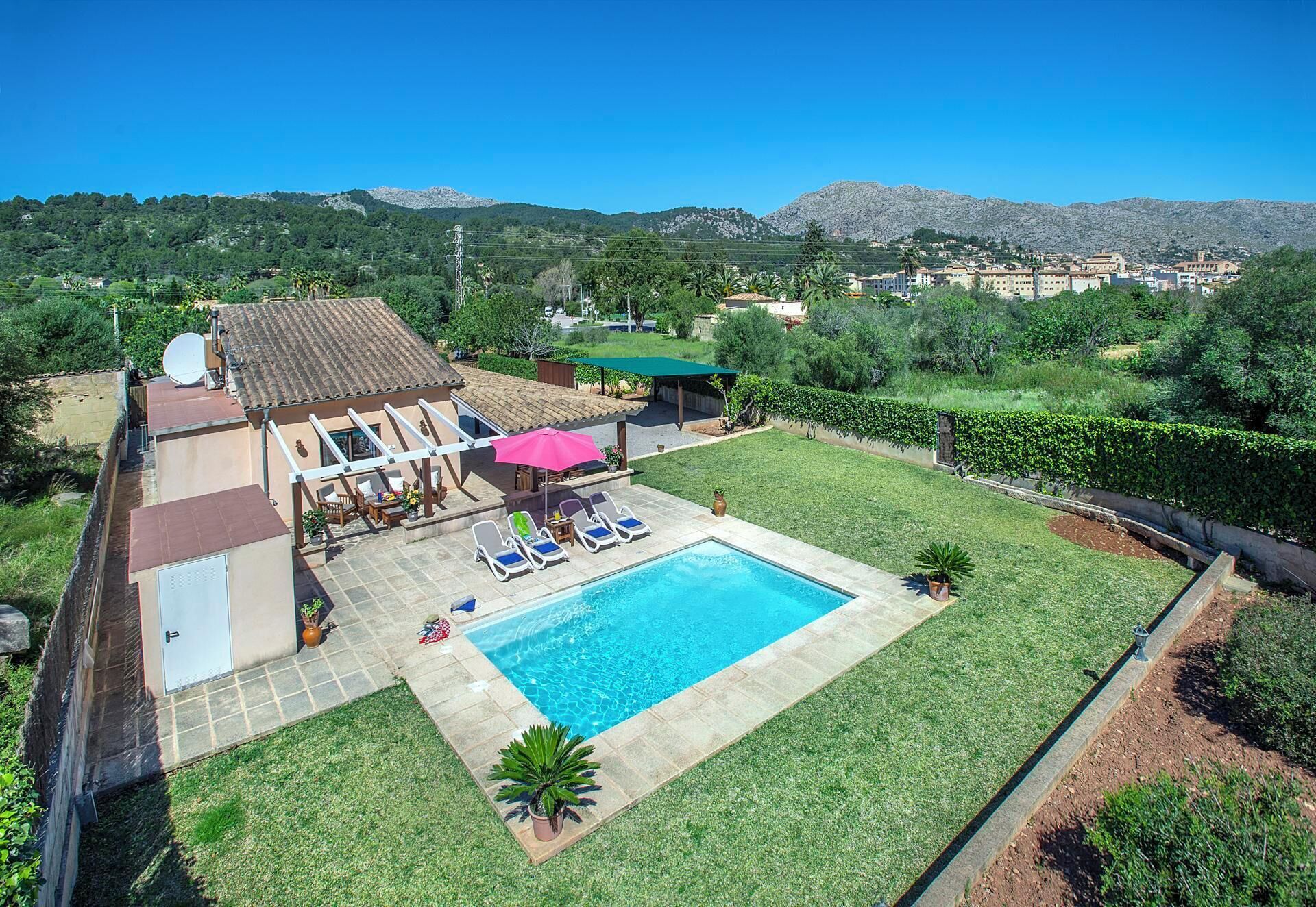 Propiedad residencial con piscina, mobiliario exterior y vistas a un paisaje montañoso.