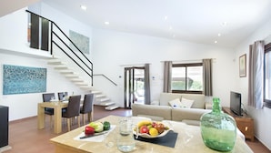 A modern living room with a kitchen island, a dining area, and a staircase. - Ca Na Lida - Two Bedroom Villa, Sleeps 4 (Mallorca)