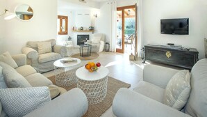 Een moderne woonkamer met een open haard, een televisie en een eethoek met uitzicht op de omgeving.