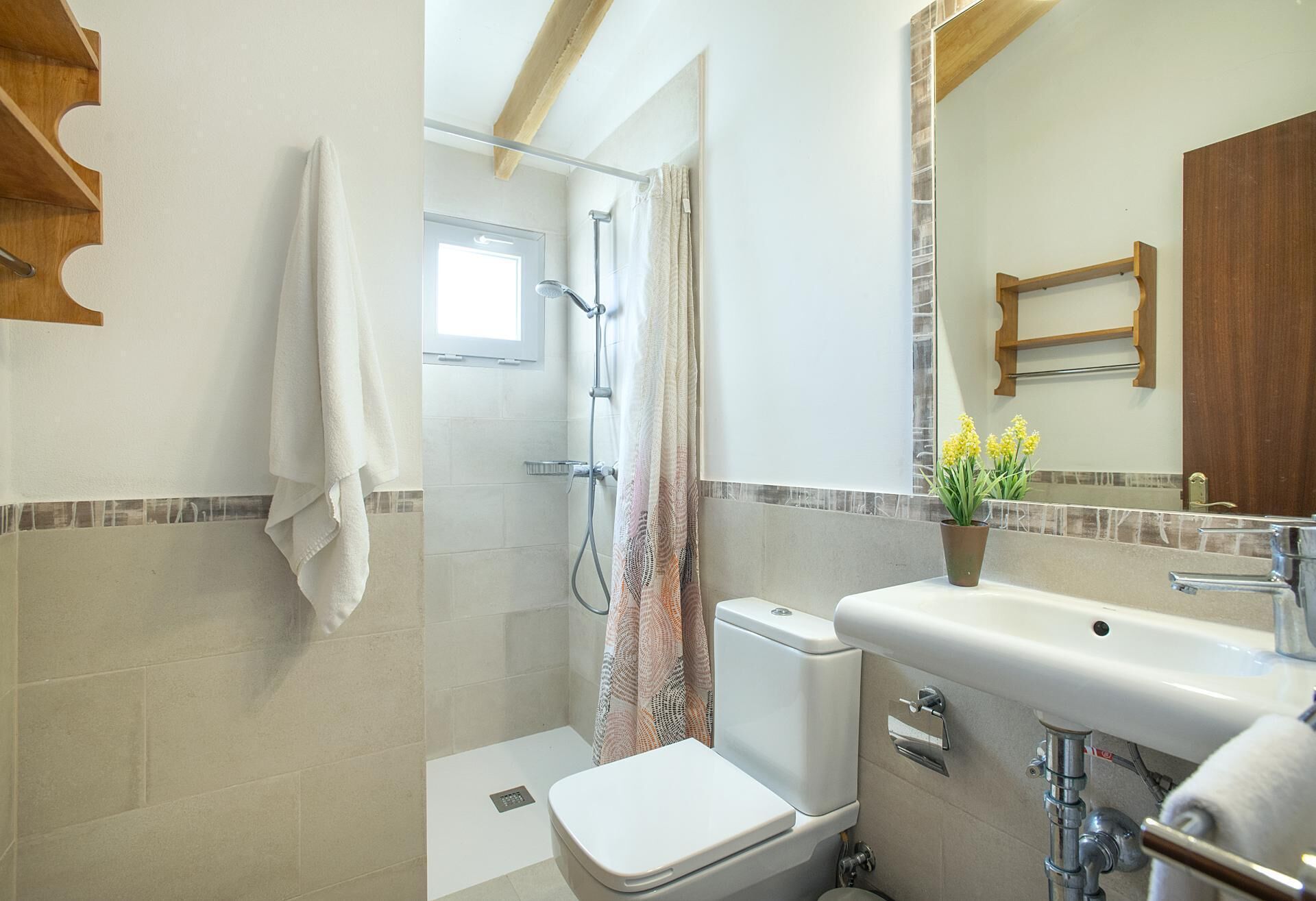 Een badkamer met een douche, toilet, wastafel en een raam.