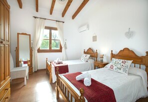 Une chambre à coucher avec deux lits en bois, un miroir, une commode et une fenêtre avec des rideaux.