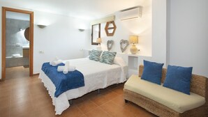 Une chambre d’hôtel comprenant un lit, un canapé, une salle de bain et un climatiseur fixé au mur.