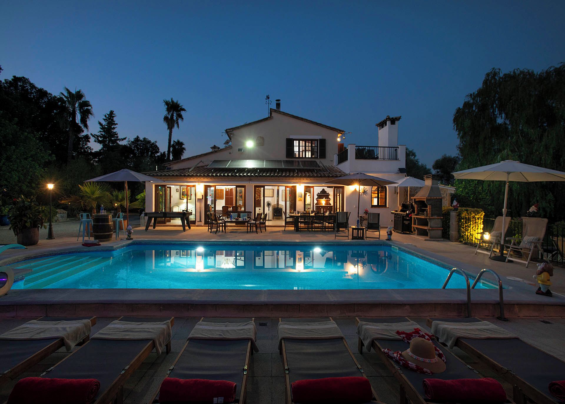 A two-story house with a swimming pool, outdoor seating, and a barbecue area.