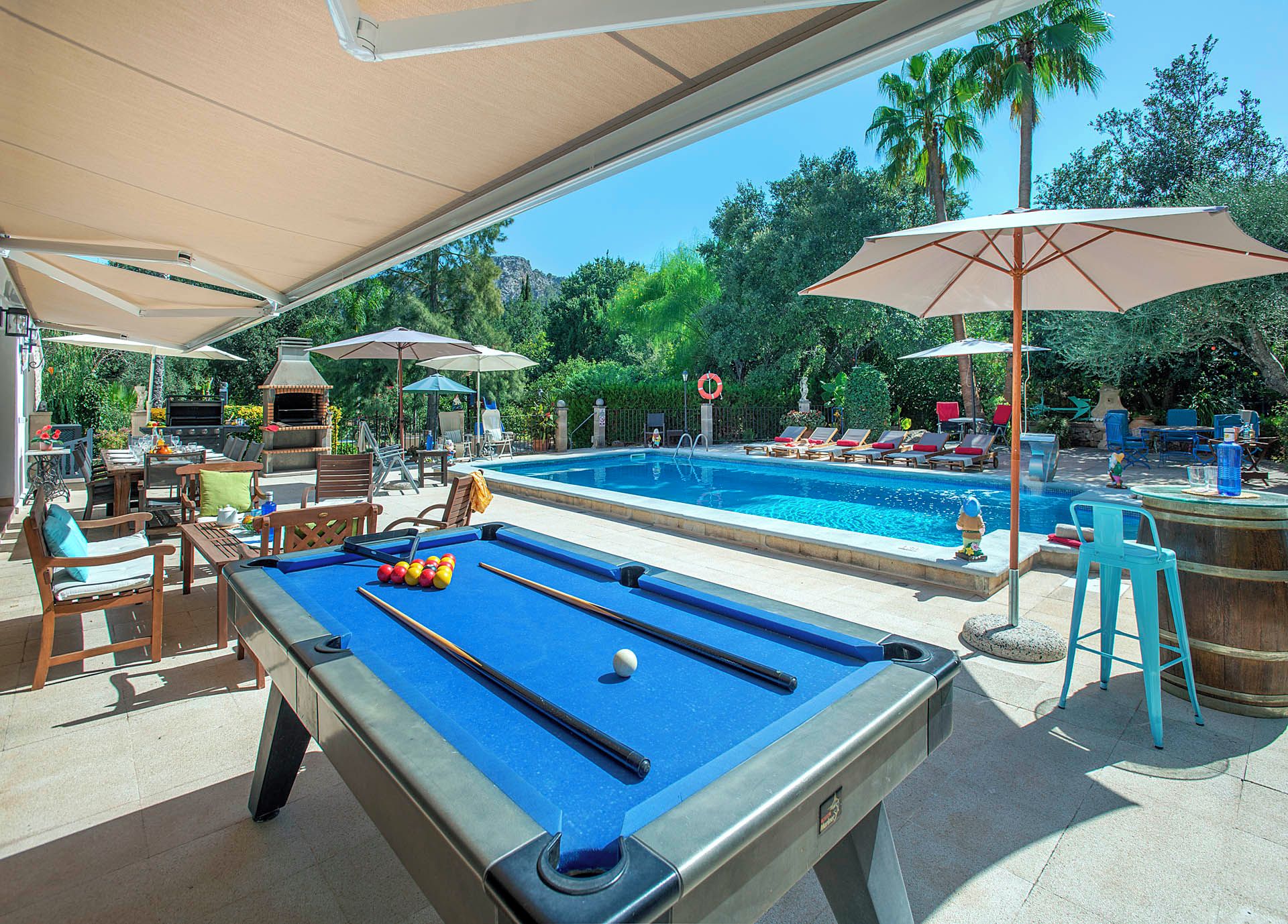 A pool area with a pool table, lounge chairs, and umbrellas.