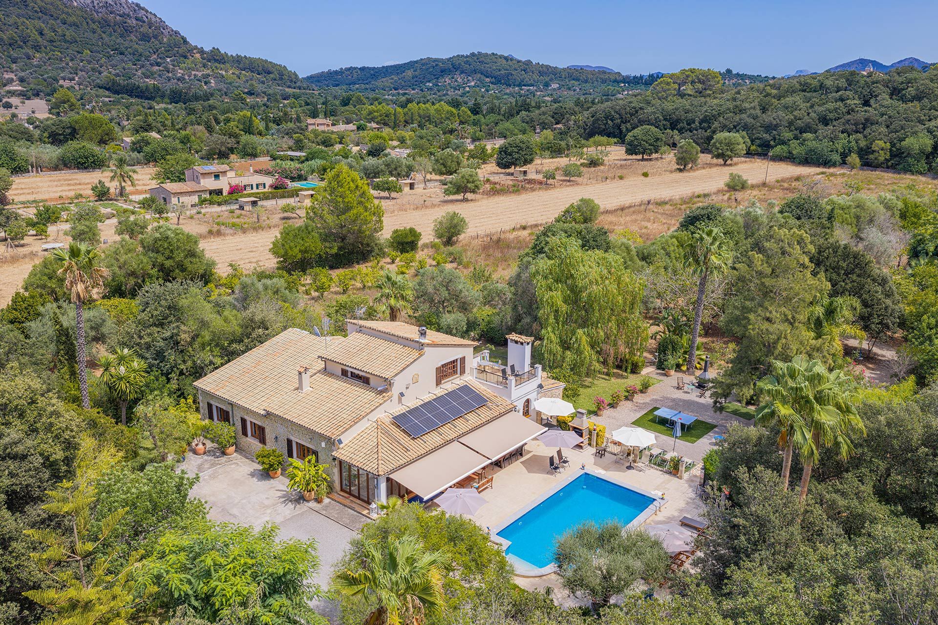 A villa with a swimming pool, surrounded by lush greenery and hills.