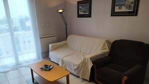 Un salon comprenant un canapé, une table basse, un lampadaire et deux tableaux encadrés accrochés au mur.