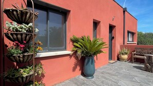A red building with a large window, a potted plant, and a bench. - Les Terres Rouges du Salagou 5min du lac ! Natura 2000 , Atelier D'artiste (Le Bosc)