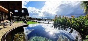 Relax by the serene pool surrounded by lush vegetation and a modern building.