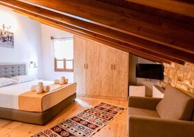 Um quarto com uma cama, um guarda-roupa de madeira, uma televisão e um tapete estampado.