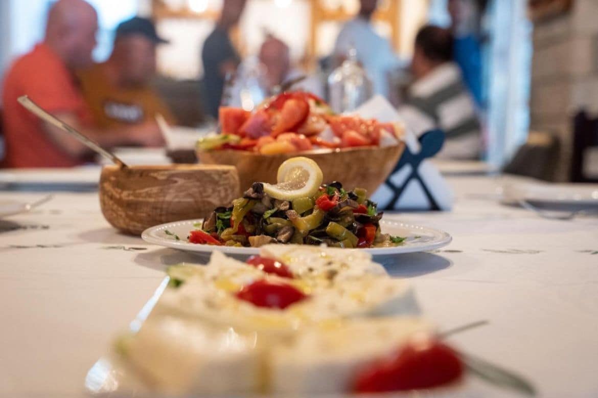 Une table à manger avec différents plats, notamment un saladier de légumes variés et une assiette qui semble contenir du houmous.