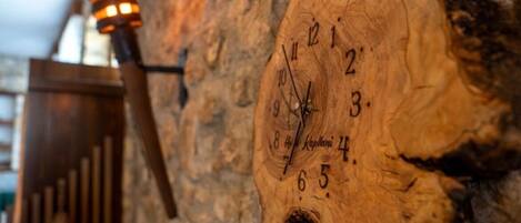 A wooden wall clock with Roman numerals and a candle holder.