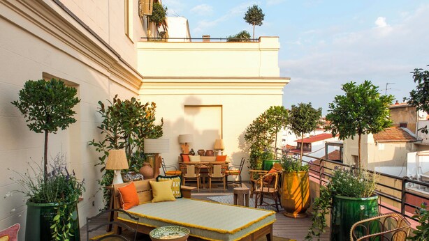 A rooftop terrace with a sofa set, dining table, chairs, and potted plants. - Brach Madrid - Evok Collection (Madrid)