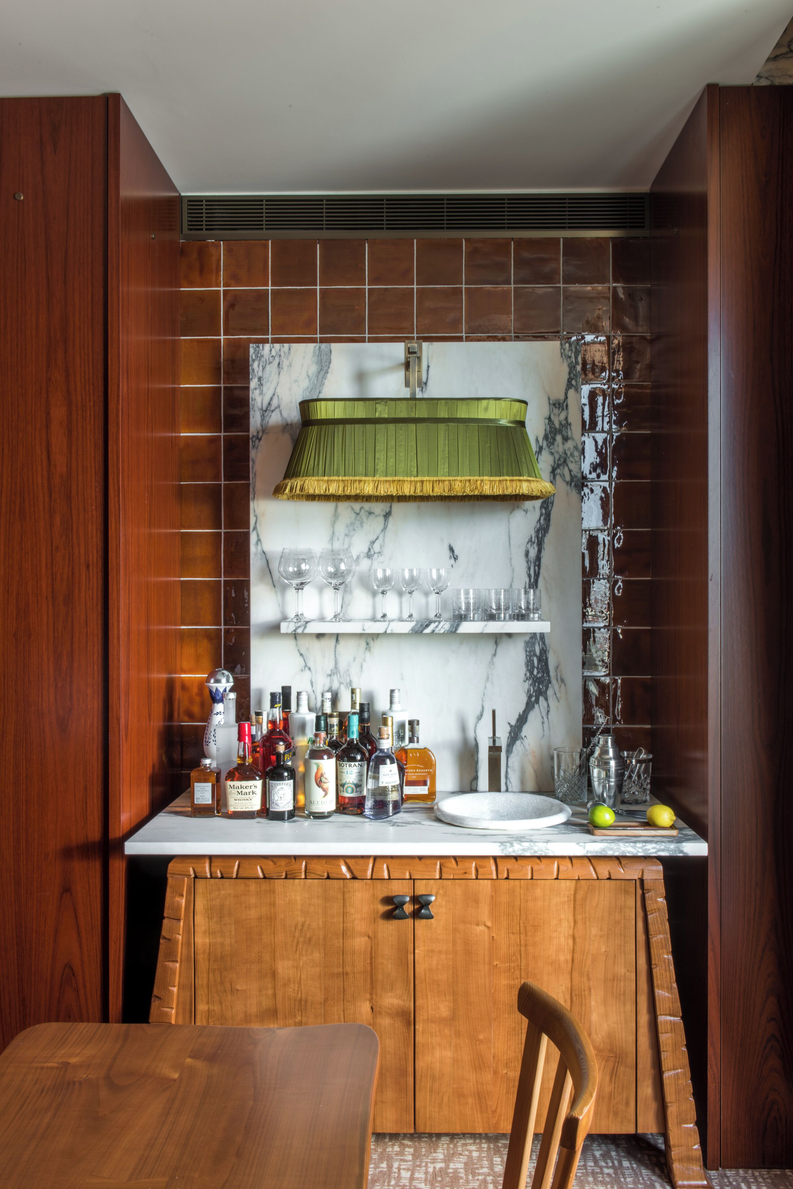 A kitchen with a wooden cabinet, a marble backsplash, and a green hanging lamp.