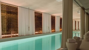 A modern hotel room with a large glass-enclosed pool, white curtains, and a view of the pool area. - Brach Madrid - Evok Collection (Madrid)
