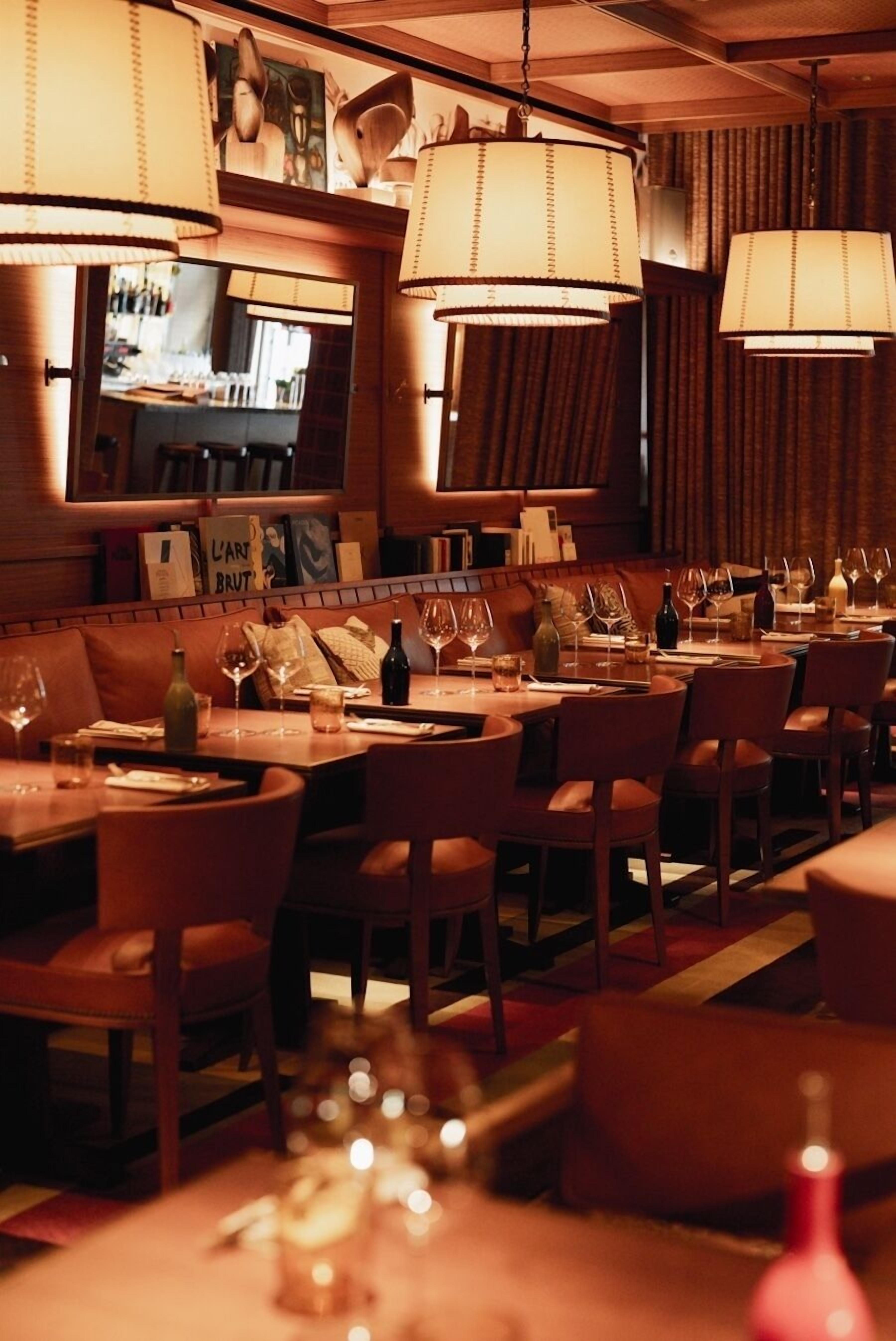 Un restaurante con varias mesas, sillas y lámparas colgantes.
