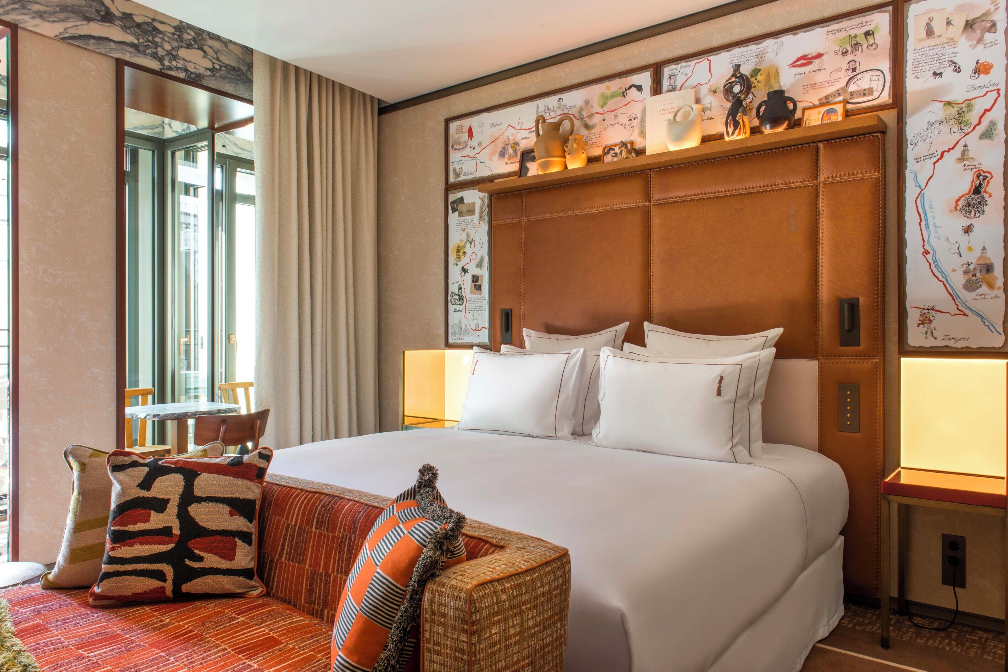 A hotel room with a large bed, a sofa, a map on the wall, and a window with curtains.