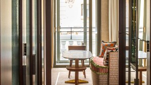 A hallway with a marble wall, a dining table with chairs, and a wicker sofa. - Brach Madrid - Evok Collection (Madrid)