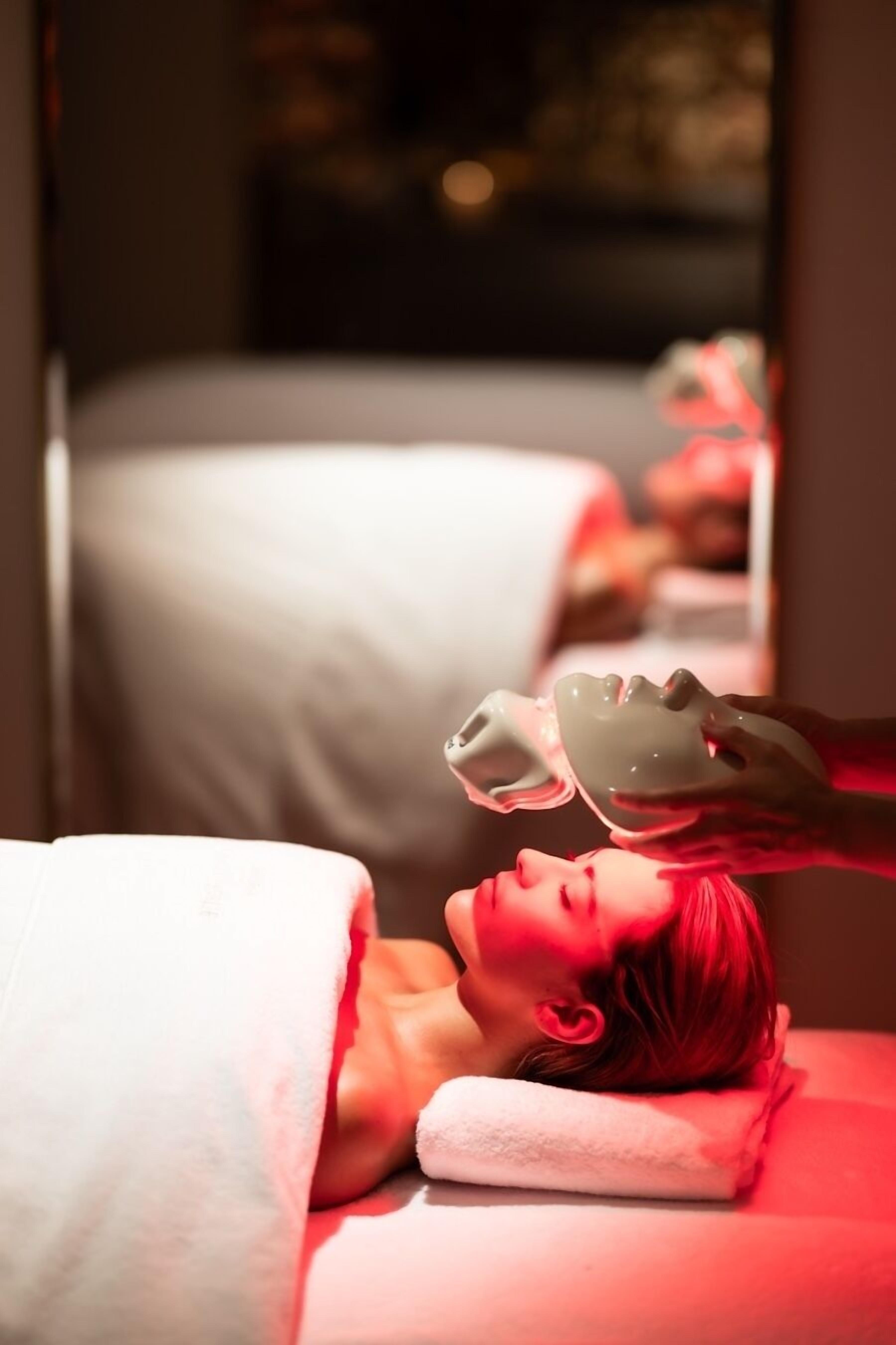 A person lying on a bed in a room with a white blanket and a pillow.