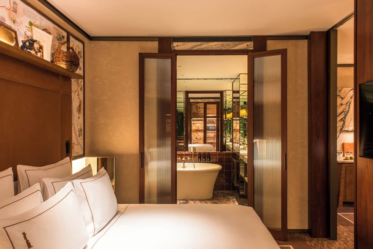 A hotel room with a large bed, a bathtub, and a shower area.