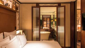 A hotel room with a large bed, a bathtub, and a shower area.