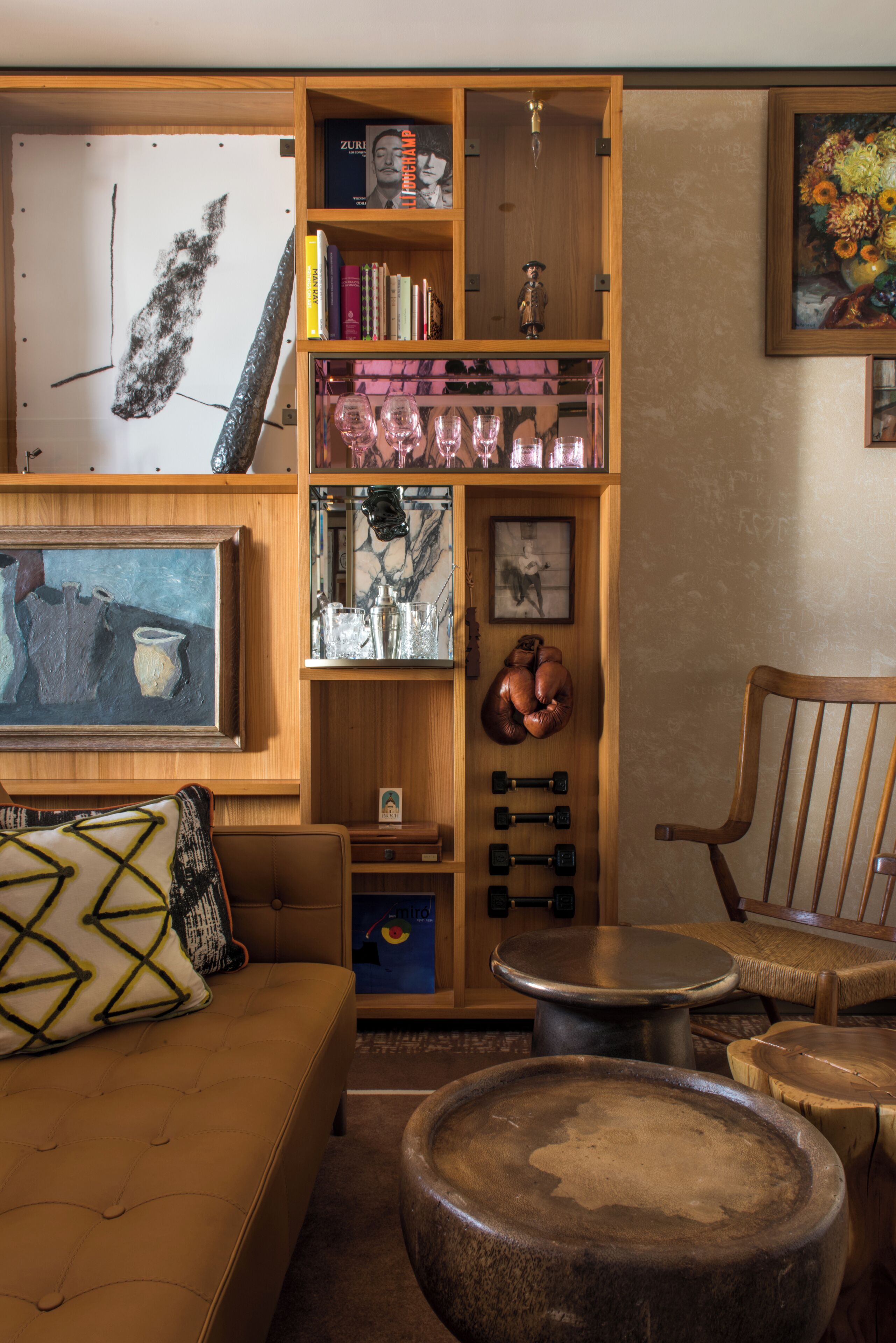 Una sala de estar acogedora con una estantería de madera, una mesa de centro, un sofá con cojines y una silla de madera.