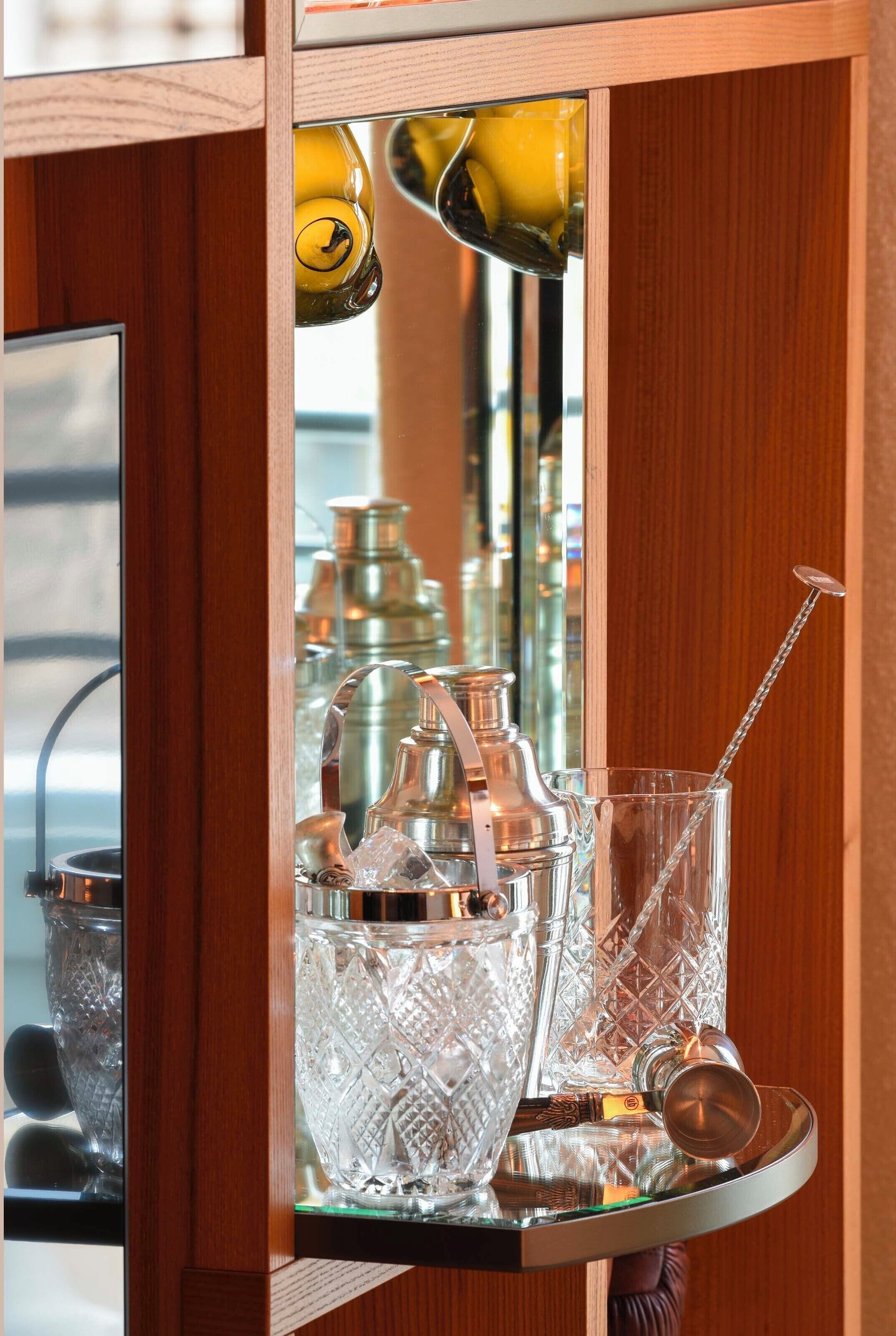 A bar area with a polished wooden bar counter, a glass display case with various bottles, and a hanging light fixture.