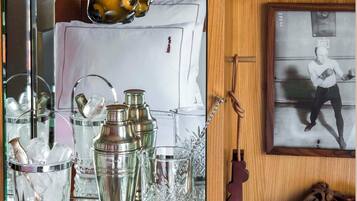 A bar area with a selection of glasses and bottles, a mirror reflecting the space, and a framed photograph on the wall.