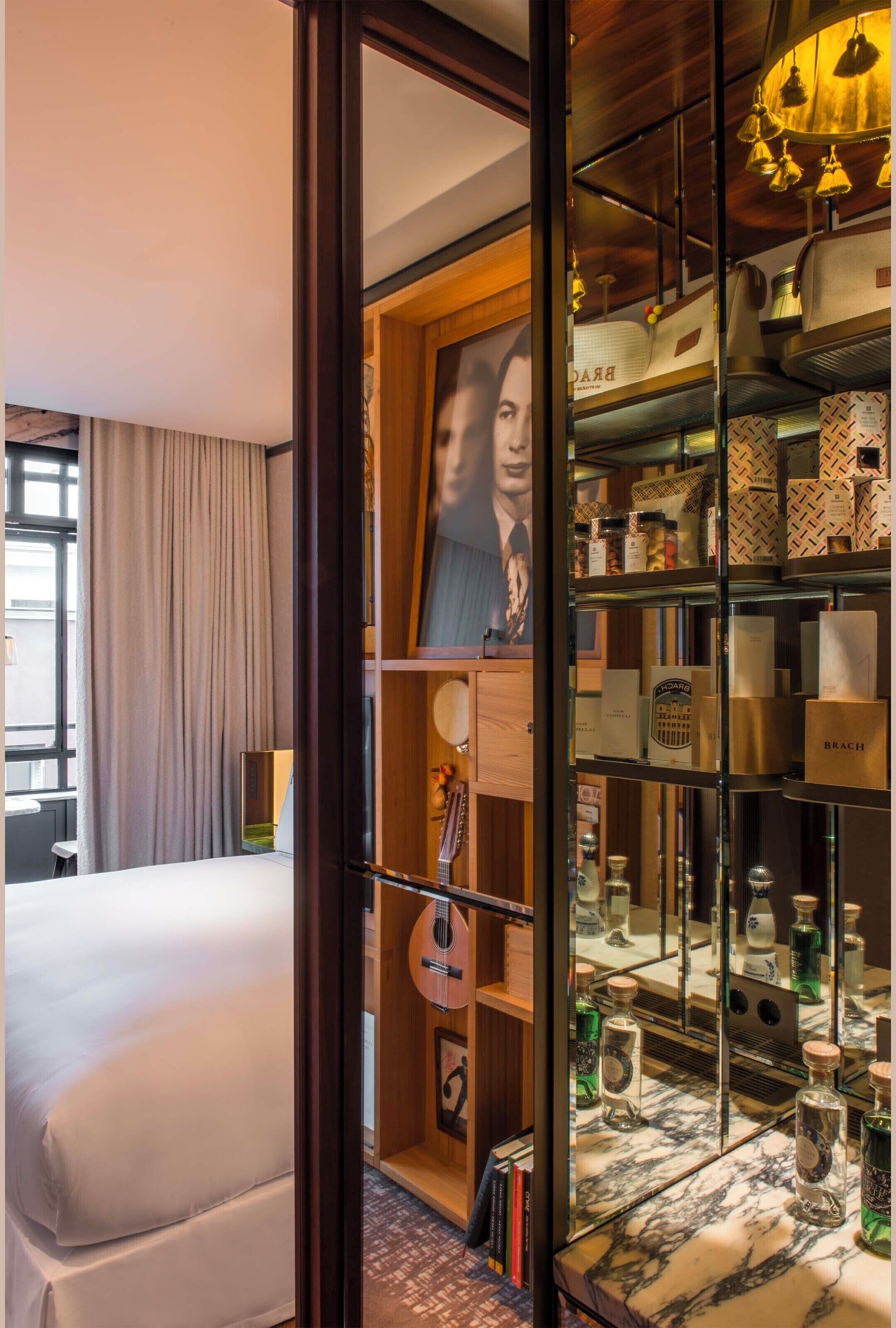 A hotel room with a large bed, a wardrobe with mirrors, and a shelf with various items.