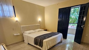 Un dormitorio con cama, mesitas de noche, un armario y una puerta que da a un balcón.