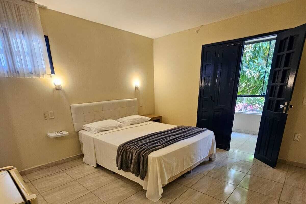 Un dormitorio con cama, mesitas de noche, un armario y una puerta que da a un balcón.