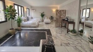 Habitació d'hotel amb un llit gran, zona de seients, bany amb banyera i mirall.